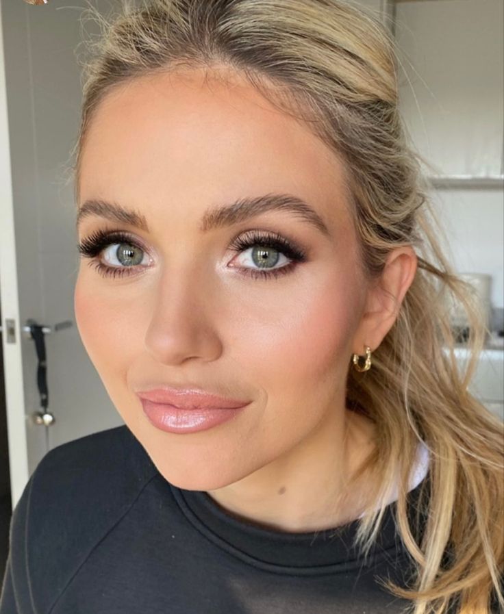 a woman with blonde hair and blue eyes is looking into the camera while wearing gold hoop earrings