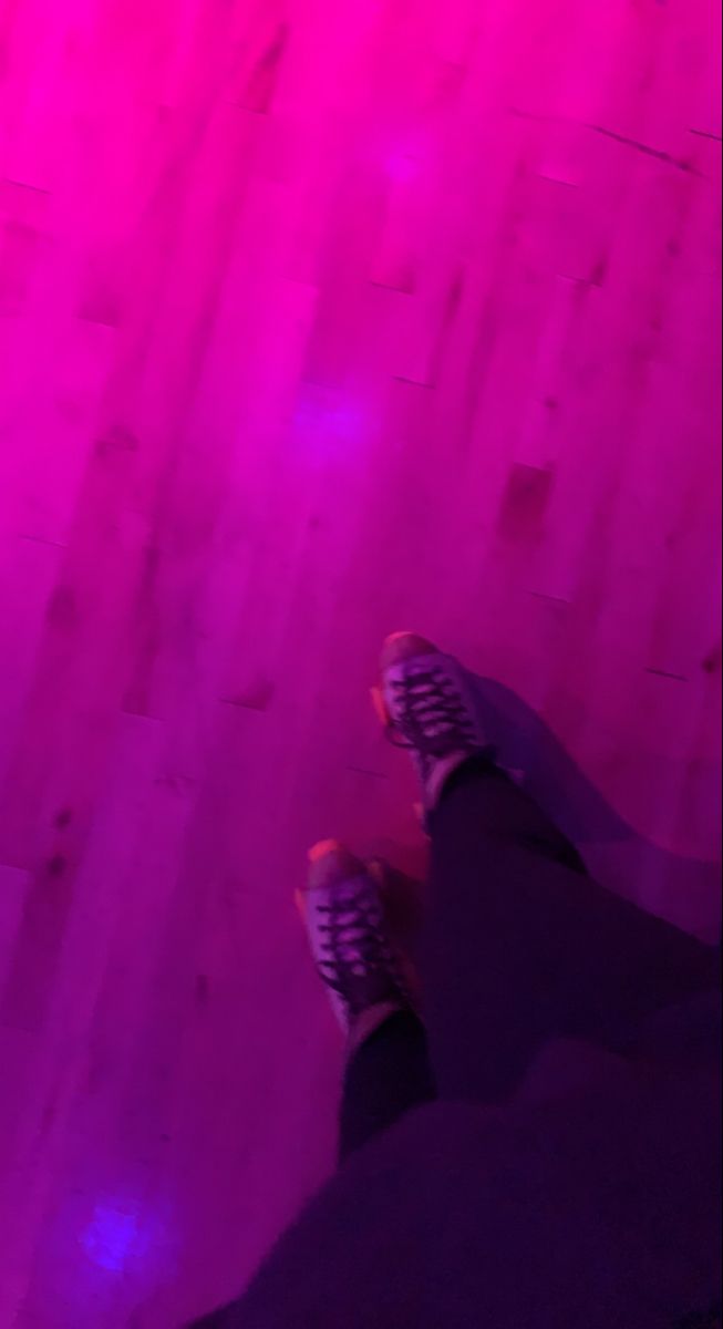 a person standing in front of a purple light with their feet up on the floor