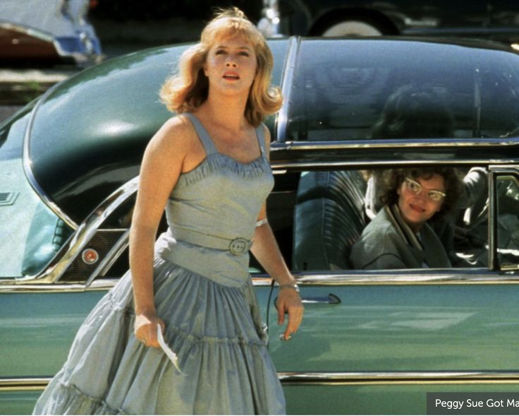 a woman standing in front of a green car