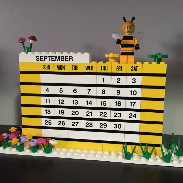 a lego calendar sitting on top of a table with a bee figurine next to it