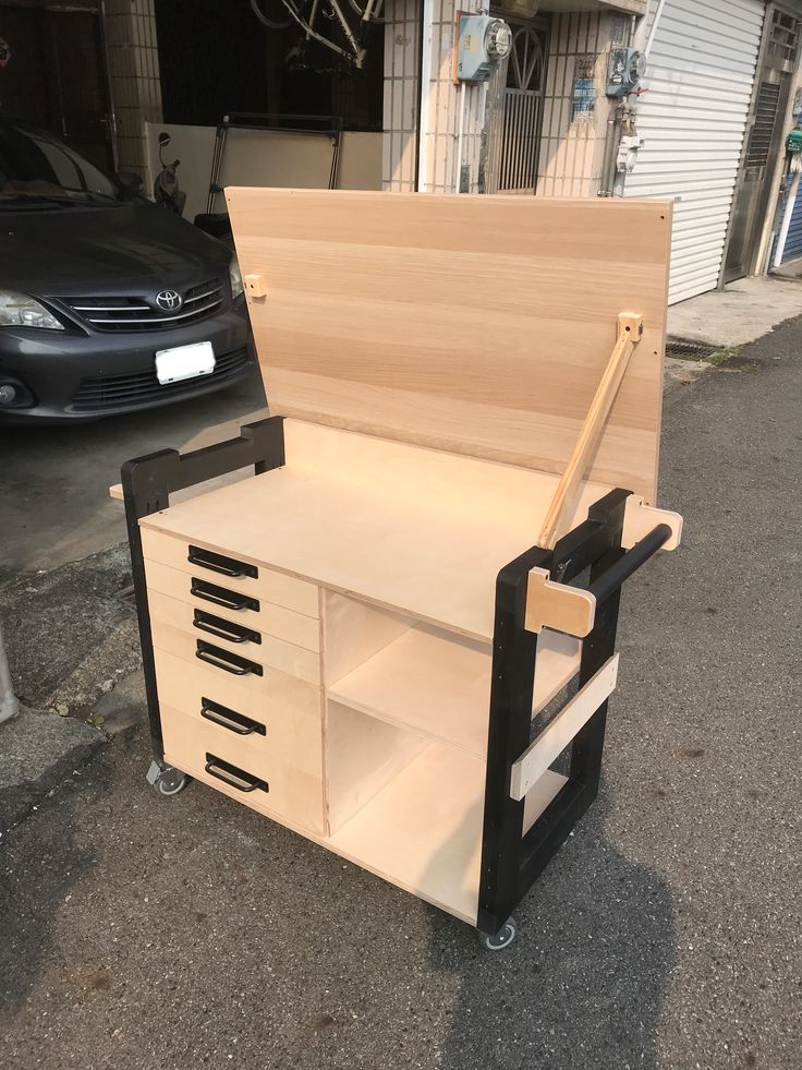 a car parked in front of a garage next to a shelf with drawers on it