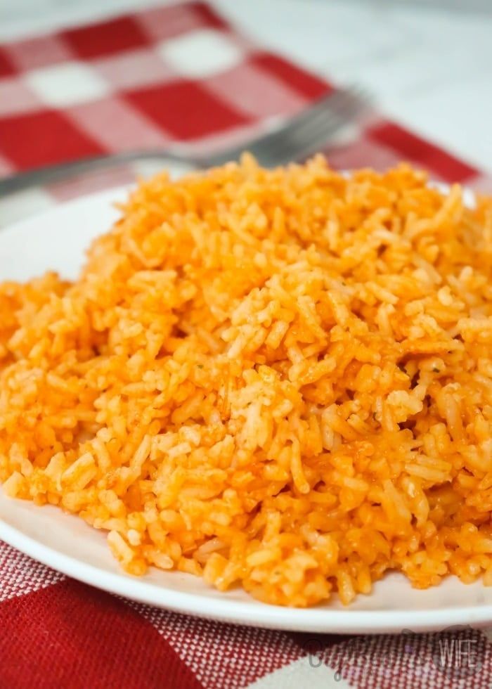 a white plate topped with rice on top of a red and white checkered table cloth