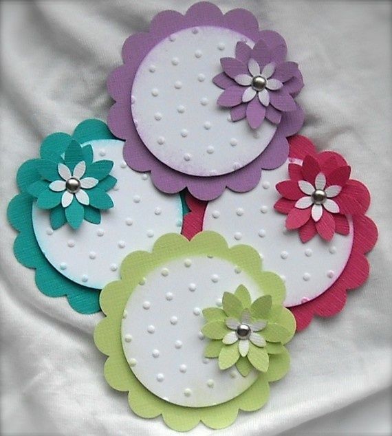 several different colored paper flowers sitting on top of a white cloth covered tablecloth with polka dots