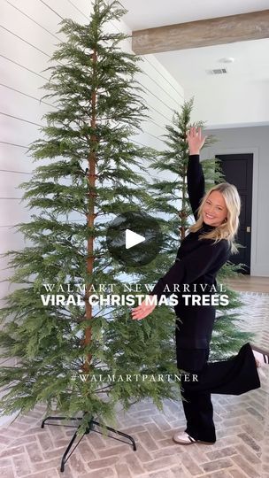 a woman standing next to a christmas tree in front of a white wall with the words virtual christmas trees on it