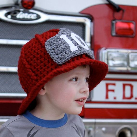 a young boy wearing a red hat standing in front of a fire truck