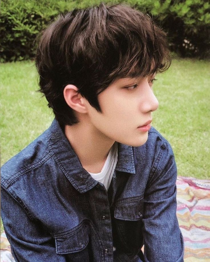 a young man sitting on top of a blanket in the grass with his eyes closed