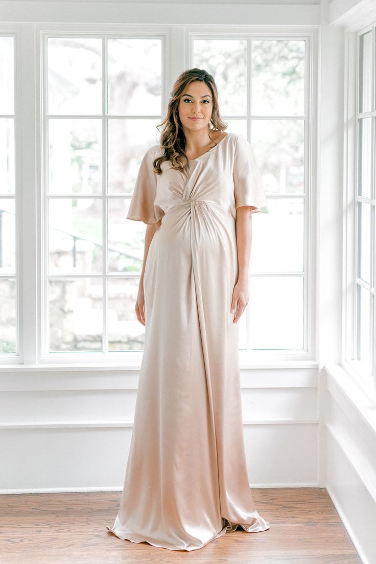 a woman standing in front of a window wearing a dress