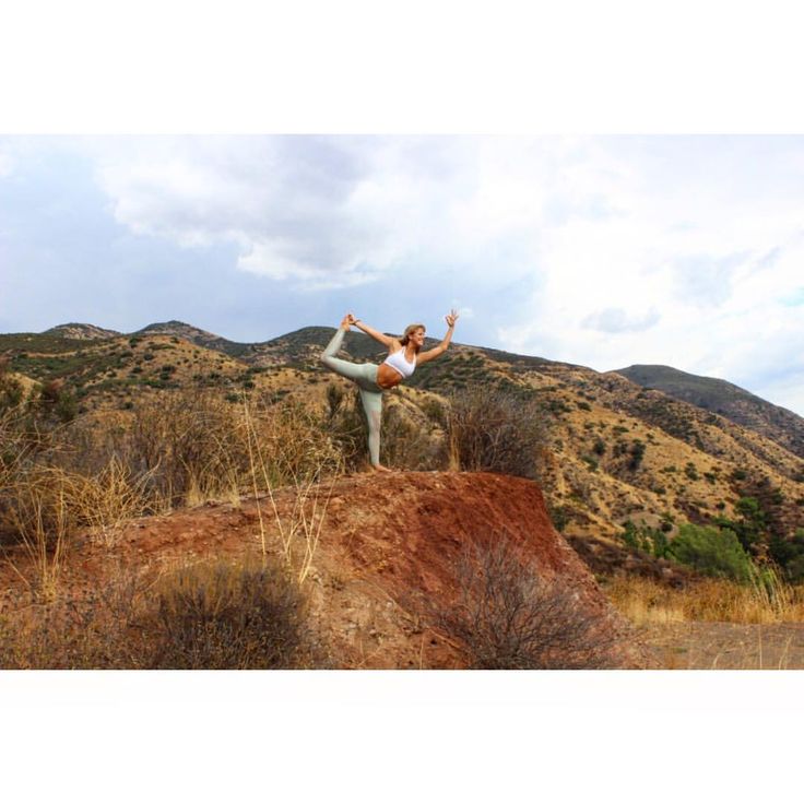 a woman doing yoga on top of a hill