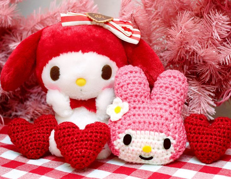 two stuffed animals sitting next to each other on a red and white checkered tablecloth