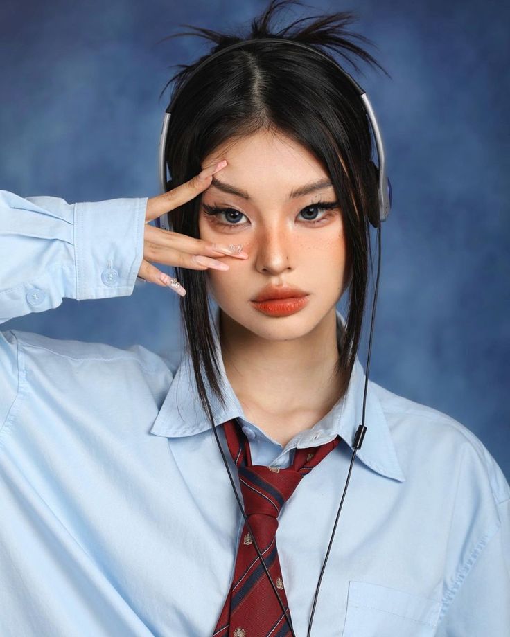 a woman with headphones on her ears and wearing a blue shirt, red tie