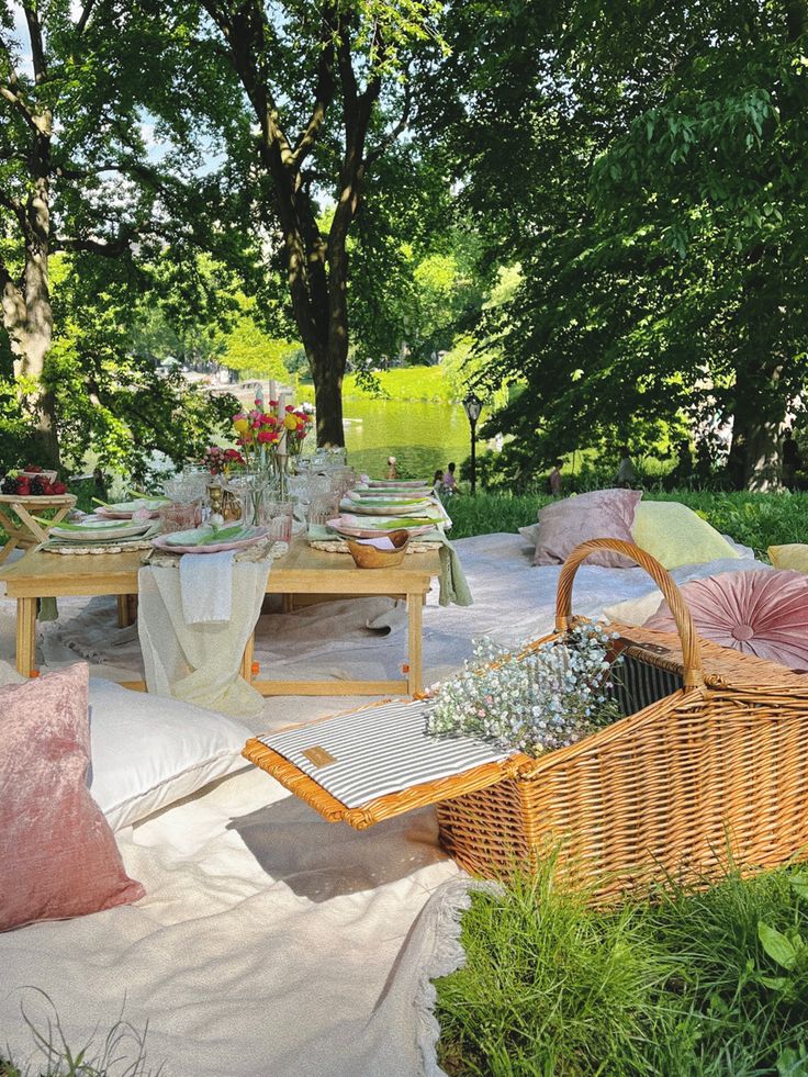 an outdoor picnic setting with wicker furniture and flowers on the table, surrounded by greenery