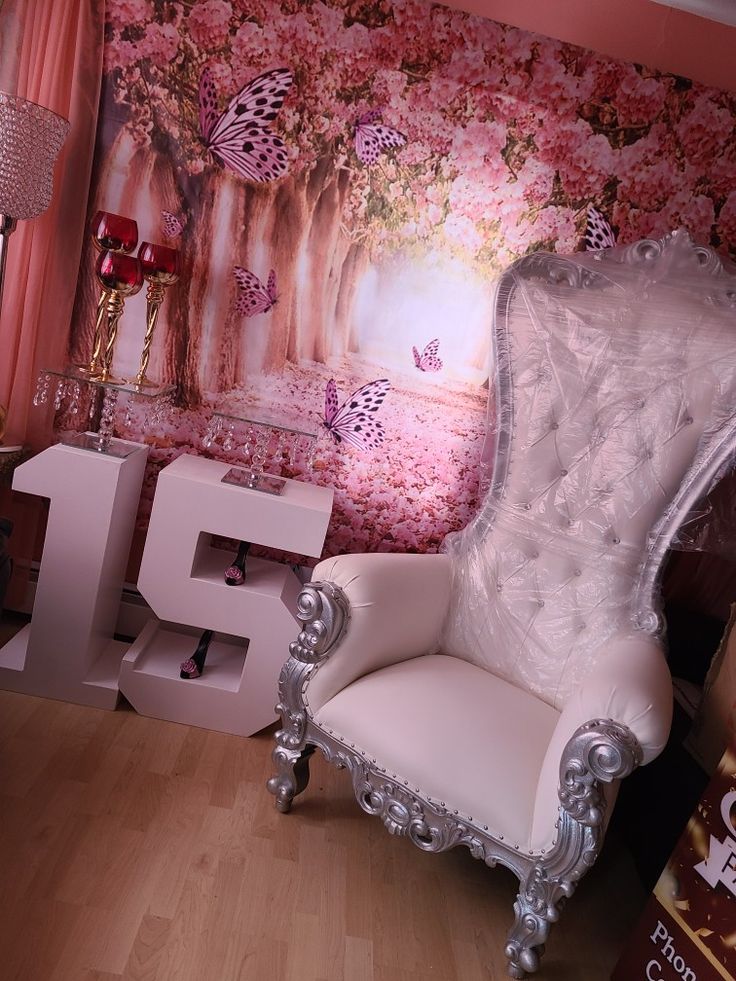 a white chair sitting next to a wall covered in pink flowers