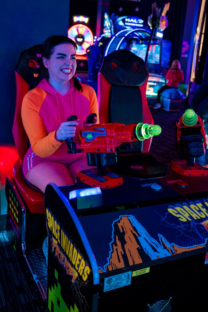 a woman sitting at a table in front of a video game machine with neon lights