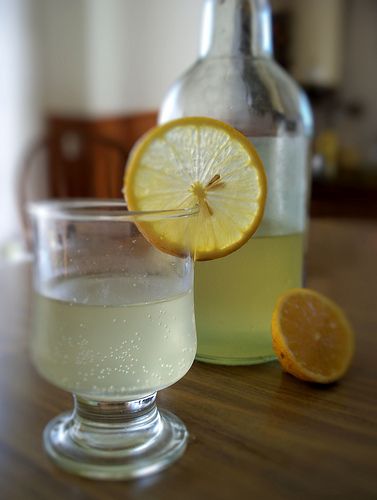 two glasses filled with lemonade sitting on top of a wooden table