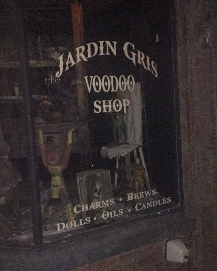 there is a store front window that has various items in the window and it says jardin gris voodoo shop