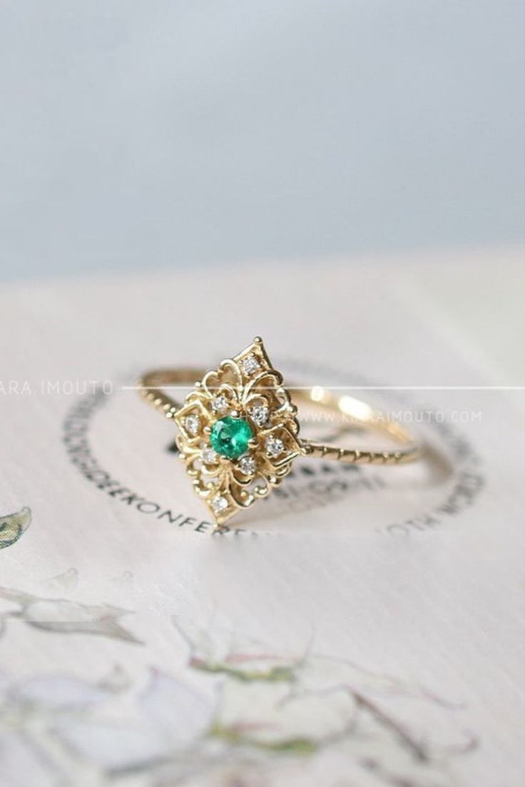 This vintage emerald ring is perfect for any occasion. #vintagejewelry #emeraldring #emeraldjewelry #vintagenegagementrings Elegant 14k Stamped Emerald Ring, Emerald Crystal Ring In Yellow Gold, Yellow Gold Emerald Crystal Ring, 14k Gold Open Emerald Ring, Fine Jewelry, 14k Gold Emerald Open Ring, Art Deco Emerald Ring With Diamond For Gift, 14k Gold Open Emerald Ring, Art Deco Emerald Ring With Diamond As Gift, Classic 14k Gold Flower Ring With Gemstone