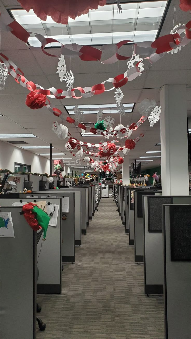 an office cubicle decorated for christmas with red and white decorations hanging from the ceiling