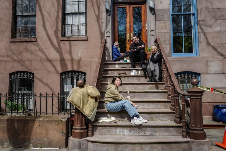 several people sitting on the steps of an old brownstone building with their feet up