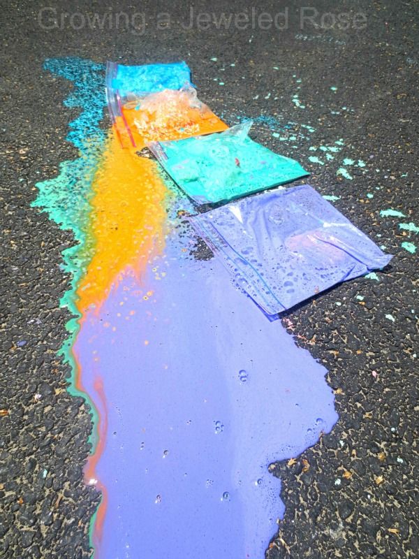 the sidewalk is littered with colored chalk and water on it's side, which has been partially melted