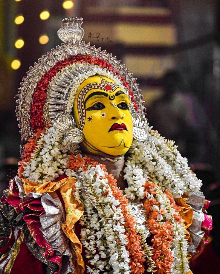 a person wearing a yellow mask and headdress with flowers on it's face