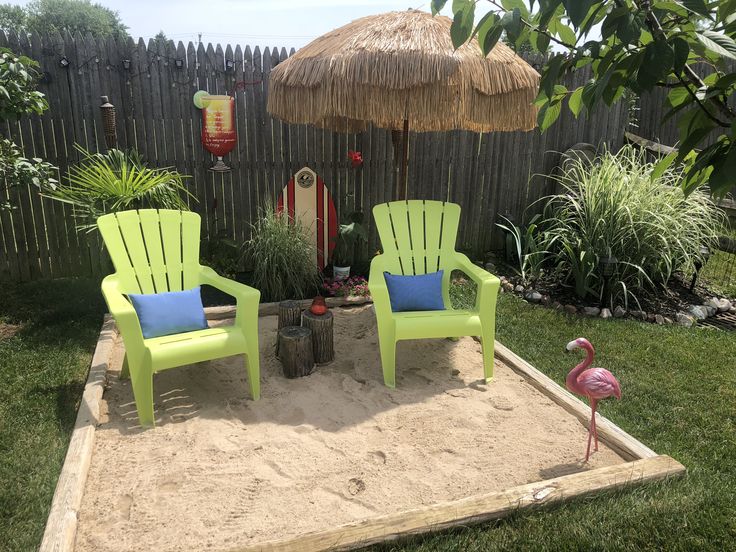 two lawn chairs sitting on top of a sandy area next to a small fire pit