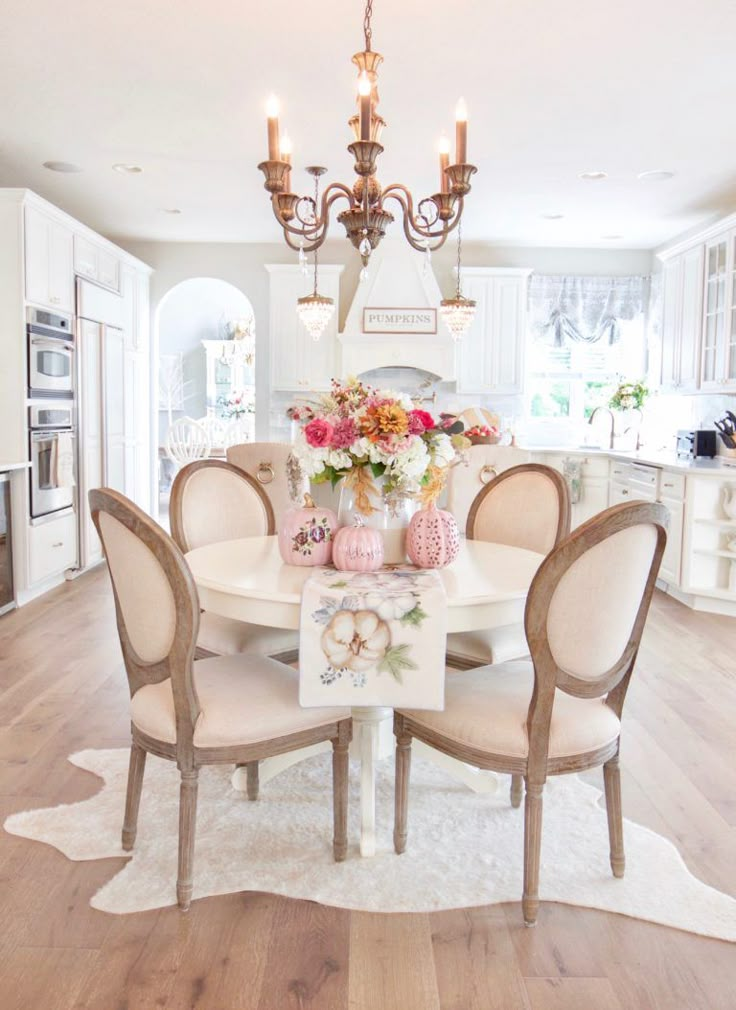 a dining room table with chairs and flowers on it