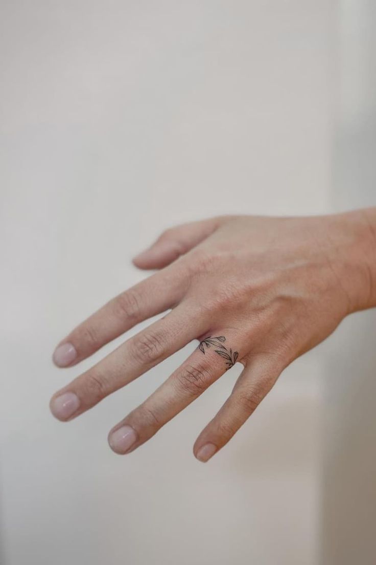 a person's hand with a ring on it and a white wall in the background