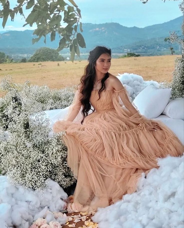 a woman sitting on top of a pile of snow next to a tree and bushes