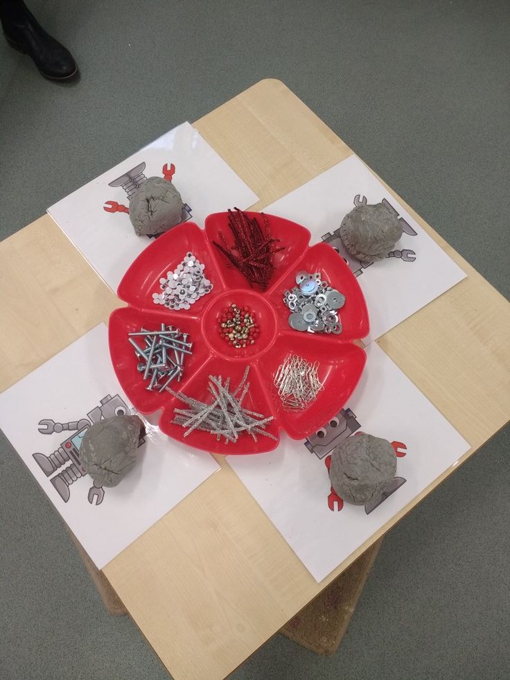 a red plate sitting on top of a wooden table covered in magnets and pins