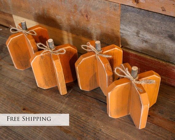 three small wooden pumpkins tied with twine on top of a wood plank floor