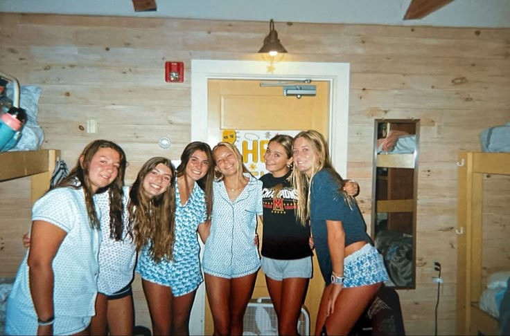 a group of young women standing next to each other in front of a wooden wall