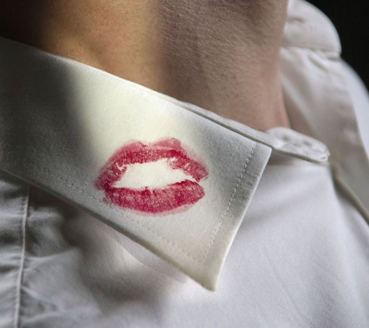 a close up of a person wearing a white shirt with a red lip print on it