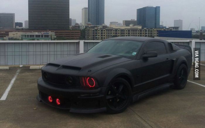 a black sports car parked in a parking lot with the city skyline in the background