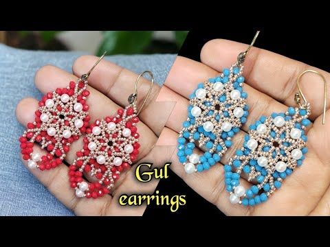 two pairs of beaded earrings in red, white and blue colors are being held by someone's hand