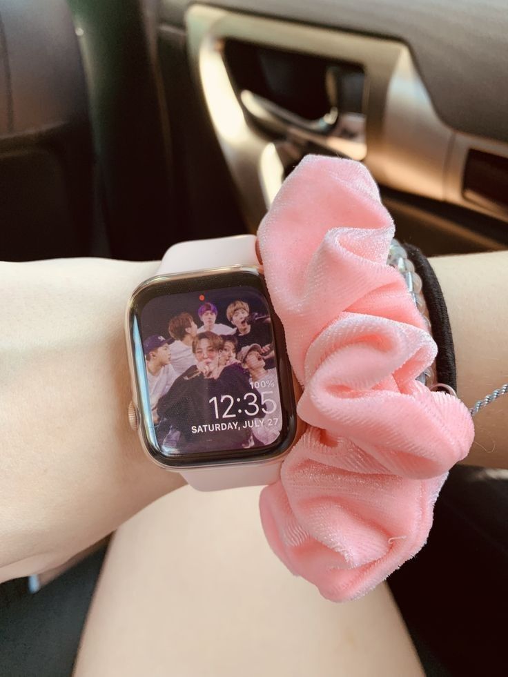 an apple watch with a pink scrunffle on it's wrist in a car