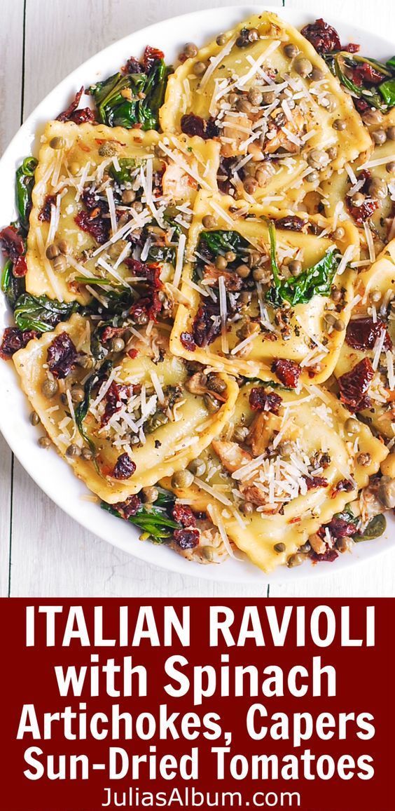 a white plate topped with pasta and spinach covered in cheese on top of a wooden table