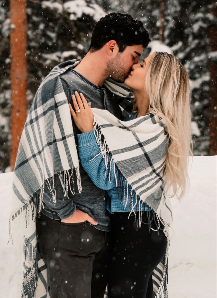 a man and woman kissing in the snow