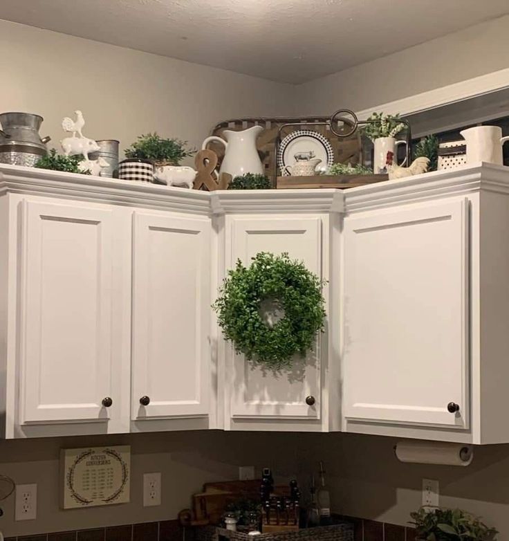 a kitchen with white cabinets and wreaths on the top