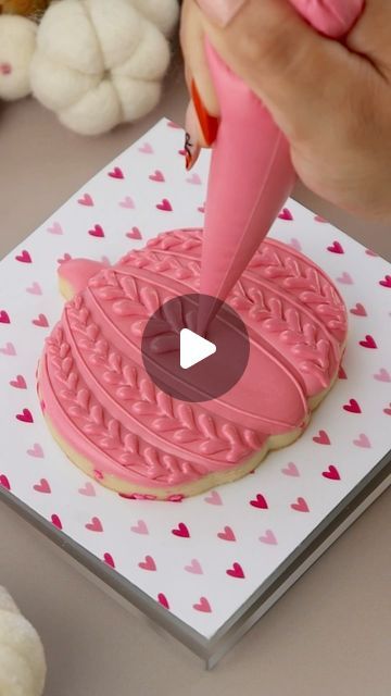 someone is decorating a cookie with pink icing