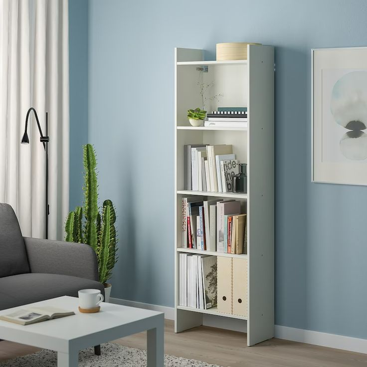 a living room with blue walls and a white bookcase filled with books next to a gray couch