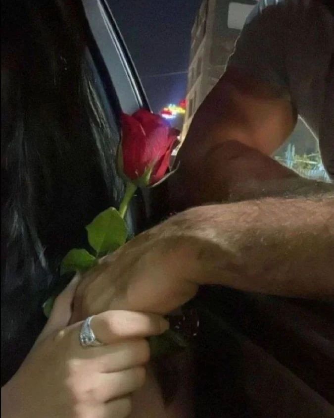 a man is holding a rose in his hand while he sits in the back seat of a car