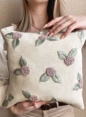 a woman holding a pillow with flowers on it