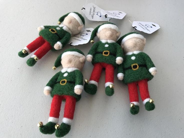 several christmas ornaments are laying on the table with tags attached to them, including one elf's head