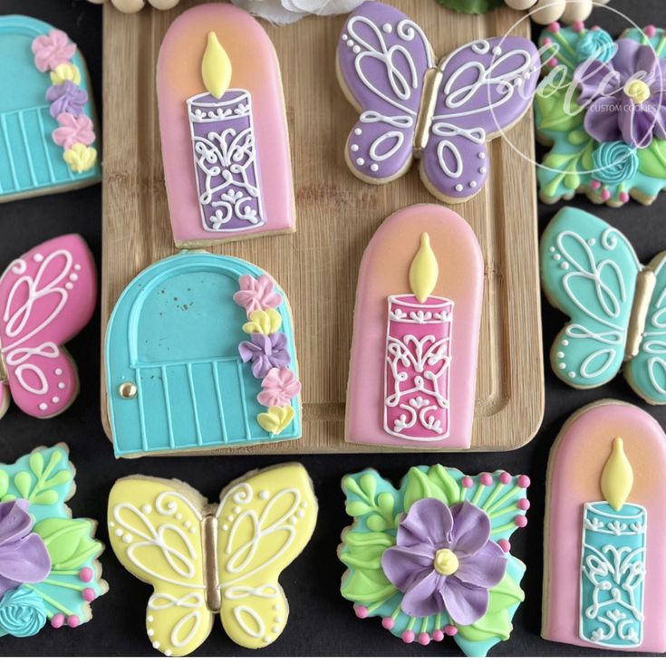 decorated cookies are arranged on a tray with flowers and candles in the shape of fairy doors