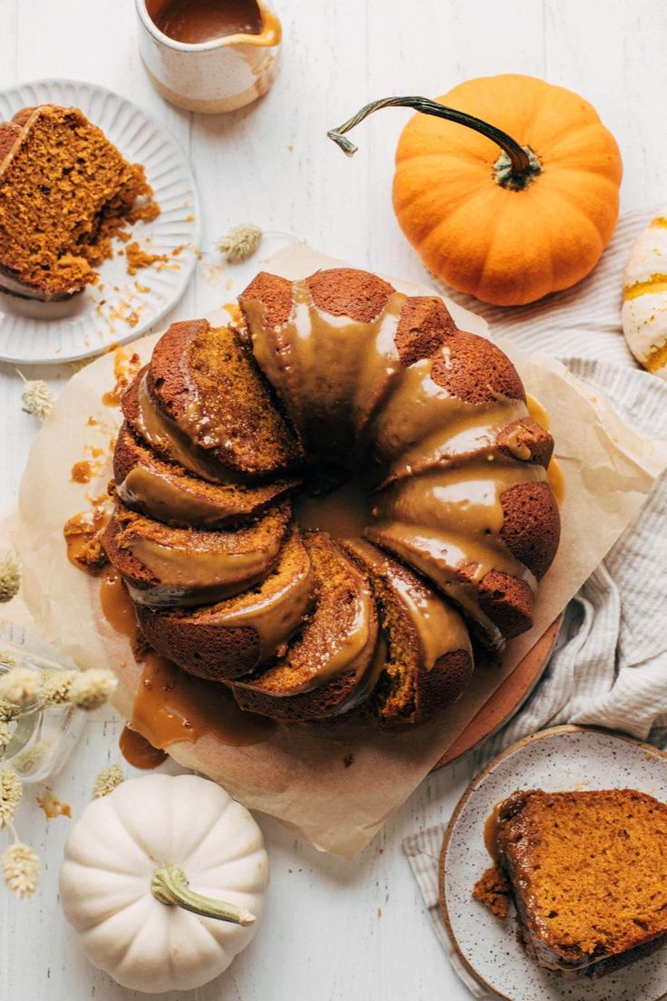 a bundt cake with caramel drizzled on top and pumpkins around it