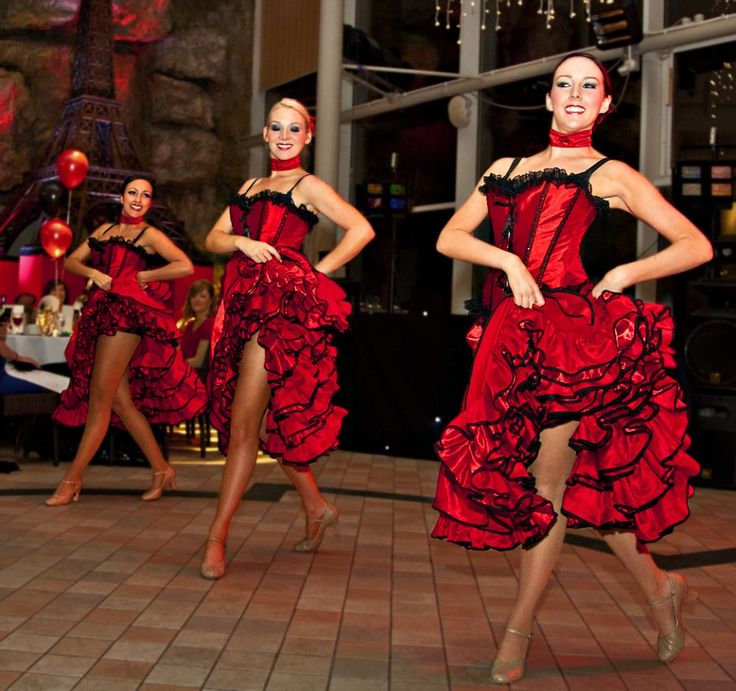 three women in red dresses are dancing on the dance floor