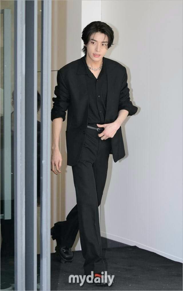 a man in a black suit walking down a hallway