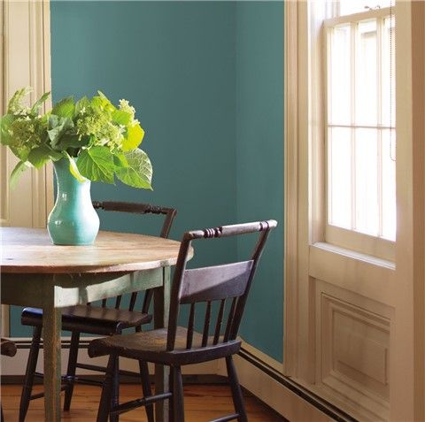 a dining room table with chairs and a vase filled with flowers on top of it