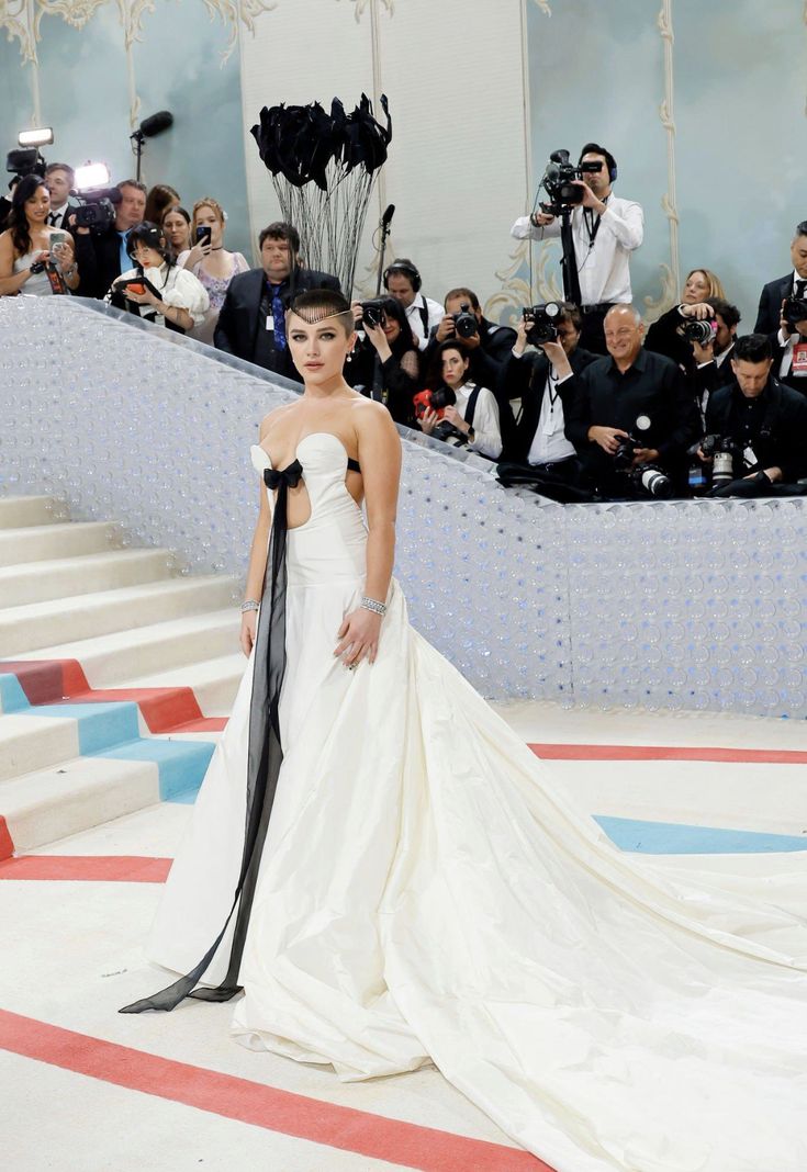 a model walks down the runway in a strapless white gown with black ribbon at the waist