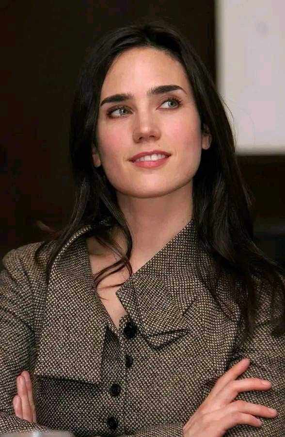 a woman with her arms crossed looking at the camera while wearing a brown and black jacket